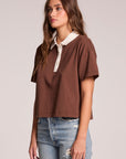 Side angle view of a woman wearing the Chaser Antoni Kahlua Tee on a neutral background with hands at her sides