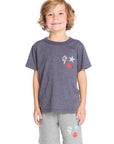 Boy wearing the Chaser Kids Bolt Star Smiley Tee in Avalon Blue with a colorful bolt, star, and smiley face design on a white background