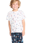 Boy wearing the Chaser Kids Allover Sailboats Tee in white with blue sailboat patterns on a white background