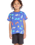 Boy wearing the Chaser Kids Cyber Surfer Tee in blue with colorful ocean and gaming graphics on a white background
