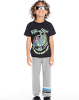 Full body view of boy wearing Chaser Kids Heather Grey Joggers and Rolling Stones Dragon Tee, styled with black sneakers and white socks on a white background