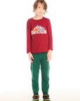 Full body view of boy wearing Chaser’s Ski Club red pullover long sleeve with SKICLUB mountain graphic and green pants on a white background