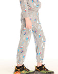 Side view of boy wearing Chaser's gray Allover Ski Slope Pants and matching top with colorful patterns on a white background