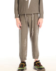 Boy wearing Chaser's green Allover Bolts Pants with lightning bolt designs on a white background