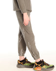 Side view of boy wearing Chaser's green Allover Bolts Pants with lightning bolt designs on a white background