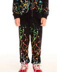 Front view of boy wearing Chaser’s Paint Splatter black pants with colorful splatter design against a white background