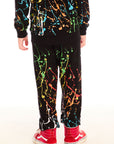Back view of boy wearing Chaser’s Paint Splatter black pants with colorful splatter design against a white background