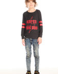 Full body view of boy wearing Chaser’s Best Brother Ever black long-sleeve shirt with red text and striped sleeves, paired with blue jeans on a white background
