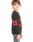 Side view of boy wearing Chaser’s Best Brother Ever black long-sleeve shirt with red text and striped sleeves, paired with blue jeans on a white background