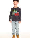 Boy wearing Chaser's Allover Racing dark gray sweatshirt with colorful graphic design, light blue jeans, and brown boots on a white background