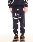 Boy wearing Chaser's navy Allover Smileys Pants with white patterns on a white background