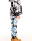 Side view of boy wearing Chaser’s Smiley Bolt tie-dye pants with and matching hoodie on a white background