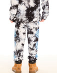 Back view of boy wearing Chaser’s Smiley Bolt tie-dye pants with matching hoodie on a white background