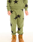 A boy wearing Chaser's Allover Stars green pant with black star patterns on a white background