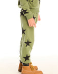 Side view of boy wearing Chaser's Allover Stars green pant with black star patterns on a white background