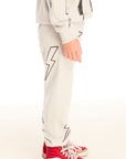 Side view of boy wearing Chaser's gray Allover Bolts pants with lightning bolt designs and on a white background