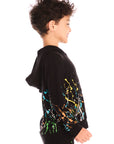 Side view of boy wearing Chaser’s Paint Splatter black hoodie with colorful splatter design and hood up on a white background