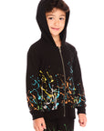 Front view of boy wearing Chaser’s Paint Splatter black zip up hoodie with colorful splatter design and hood up on a white background