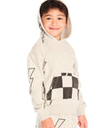 Side view of boy wearing Chaser’s Blocked Checkered Bolts light gray hoodie with hoodie up with checkered pattern and lightning bolt designs on a white background