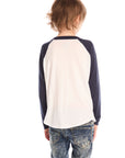 Back view of boy wearing Chaser’s The Beatles Abbey Road football tee in white with navy blue sleeves and jeans on a white background