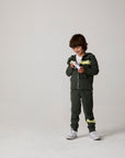 Model wearing Chaser's Lime Stripe Boys Zip-Up Hoodie in leafy green with striped detailing, editorial view