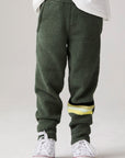 Model wearing Chaser's Lime Stripe Boys Lounge Pants in leafy green with striped detailing, front view