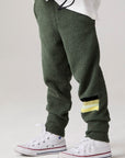 Model wearing Chaser's Lime Stripe Boys Lounge Pants in leafy green with striped detailing, side view