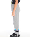 Side view of boy wearing Chaser Kids Heather Grey Joggers showing relaxed fit and stripe detail near the ankle, styled with black sneakers on a white background