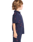 Side view of boy wearing the Chaser Kids Collared Avalon Lobsters Shirt showing short sleeves, button-front design, and relaxed fit, styled with matching shorts and navy sneakers on a white background