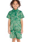 Front view of boy wearing the Chaser Kids Wild Green Tie Dye Polo Shirt featuring a button placket and spiral tie dye pattern, paired with matching Wild Green Tie Dye Cozy Beach Shorts on a white background