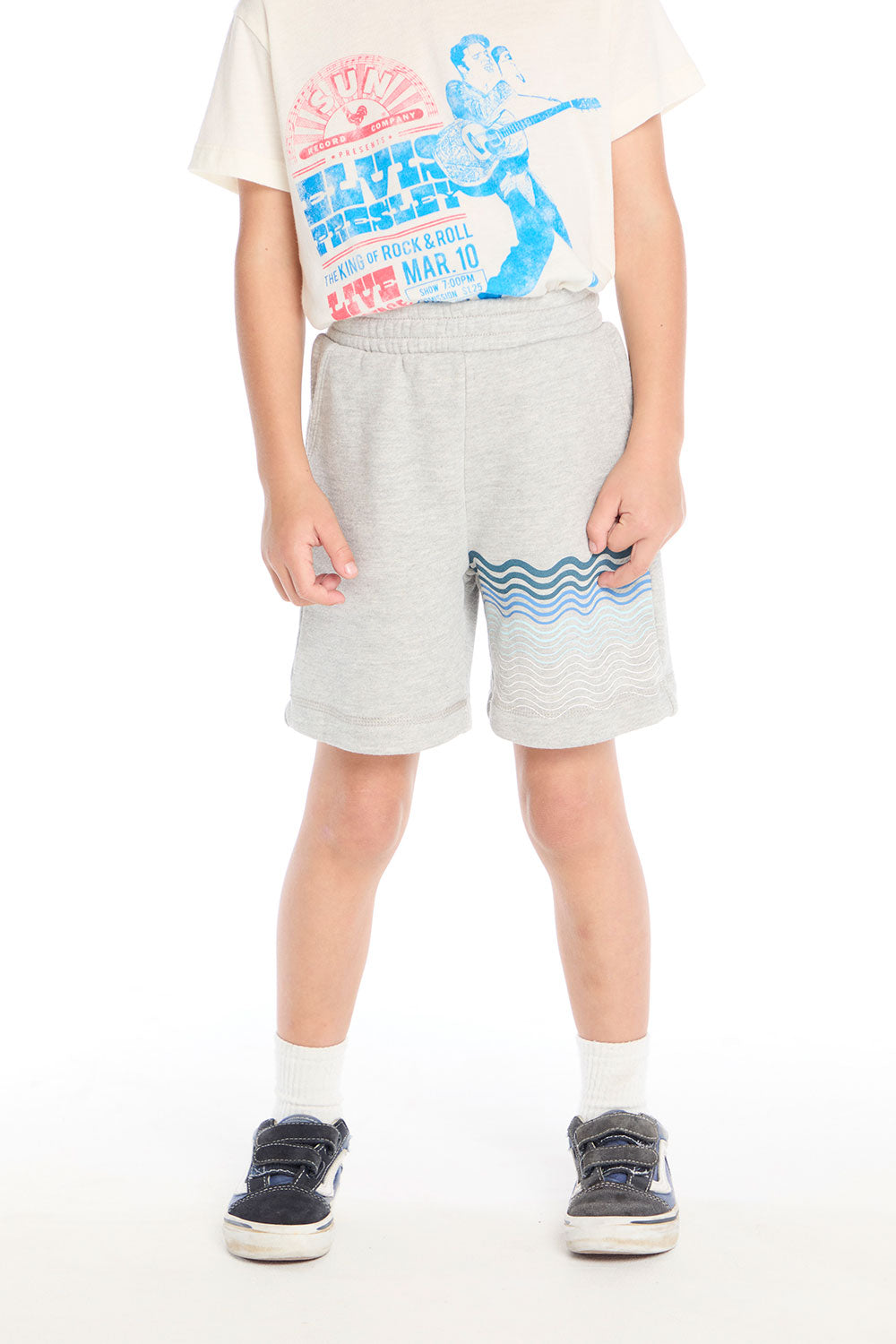 Front view of boy wearing the Chaser Kids Peace Out Shorts in Heather Grey featuring blue wave graphics near the hem, paired with an Elvis Presley graphic tee on a white background