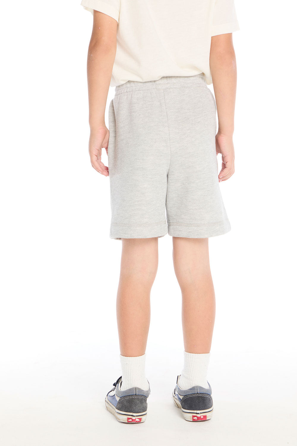 Back view of boy wearing the Chaser Kids Peace Out Shorts in Heather Grey paired with a white tee and navy sneakers on a white background