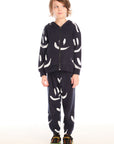 Full body view of boy wearing Chaser’s Smileys navy blue zip up hoodie with white smiley face patterns and matching pants on a white background