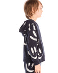 Side view of boy wearing Chaser’s Smileys navy blue zip up hoodie with white smiley face graphics against a white background