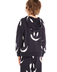 Back view of boy wearing Chaser’s Smileys navy blue zip up hoodie with allover white smiley face print against a white background