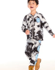 Full body view of boy wearing Chaser’s Smiley Bolt tie-dye pants with matching hoodie on a white background