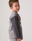 Model wearing Chaser's Heroes Boys Long Sleeve Tee in charcoal with first-responder vehicle graphics, side view