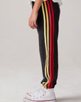 Model wearing Chaser's Vintage Black Stripe Boys Lounge Pants in Black with striped detailing, side view