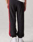 Model wearing Chaser's Vintage Black Stripe Boys Lounge Pants in Black with striped detailing, back view