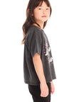 Side view of young girl wearing Chaser’s Best Sister black tee on a white background