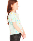 Side view of girl wearing Chaser’s light green Unicorn Hearts Tee with colorful graphic details against a white background