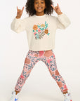Child wearing a floral sweatshirt and leggings on a white background