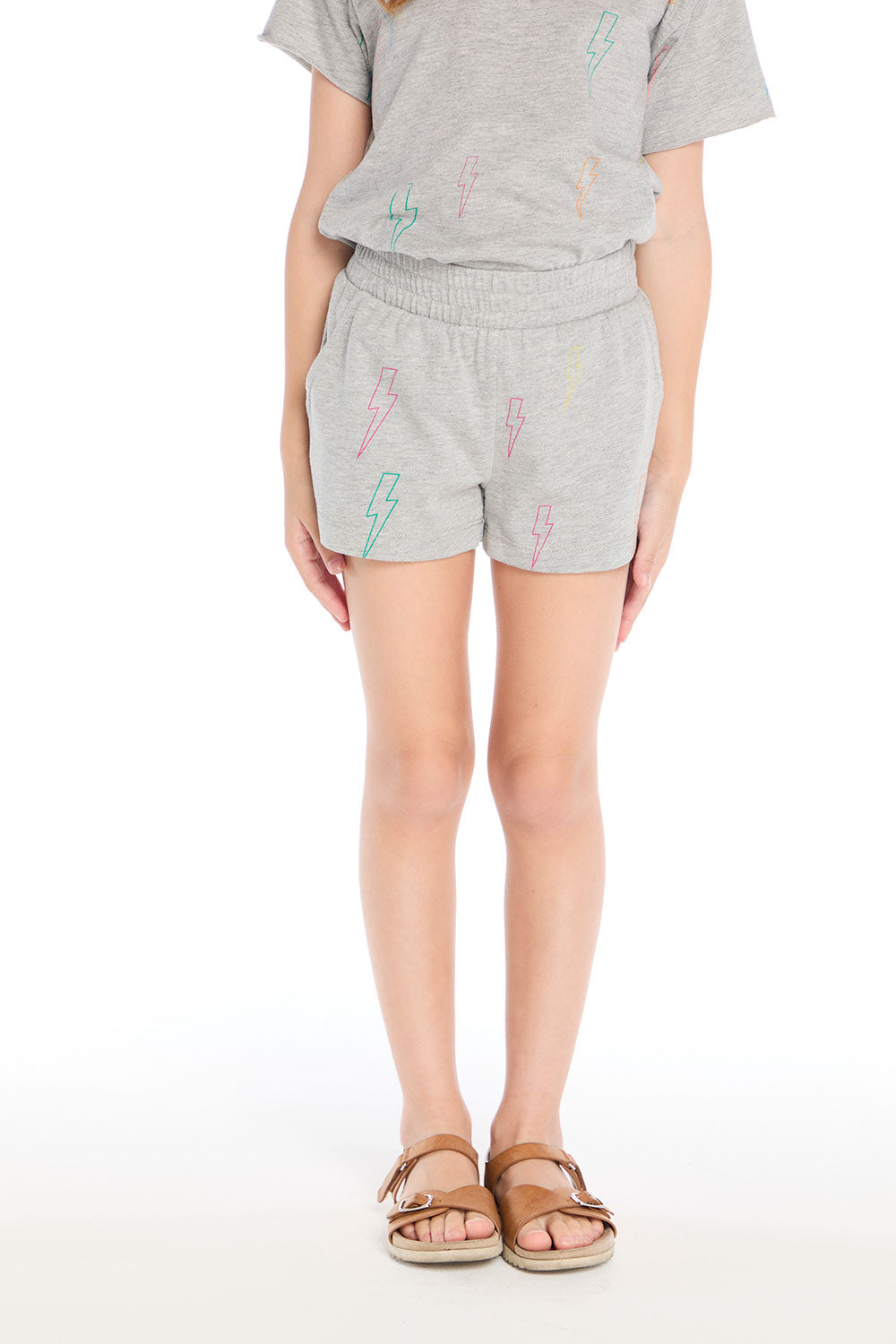 Girl wearing the Chaser Kids Neon Bolts Shorts in Heather Grey featuring a colorful lightning bolt print and elastic waistband