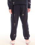 Back view of girl wearing Chaser’s navy blue Tossed Glitter Bows Pants with embroidered bows on a white background