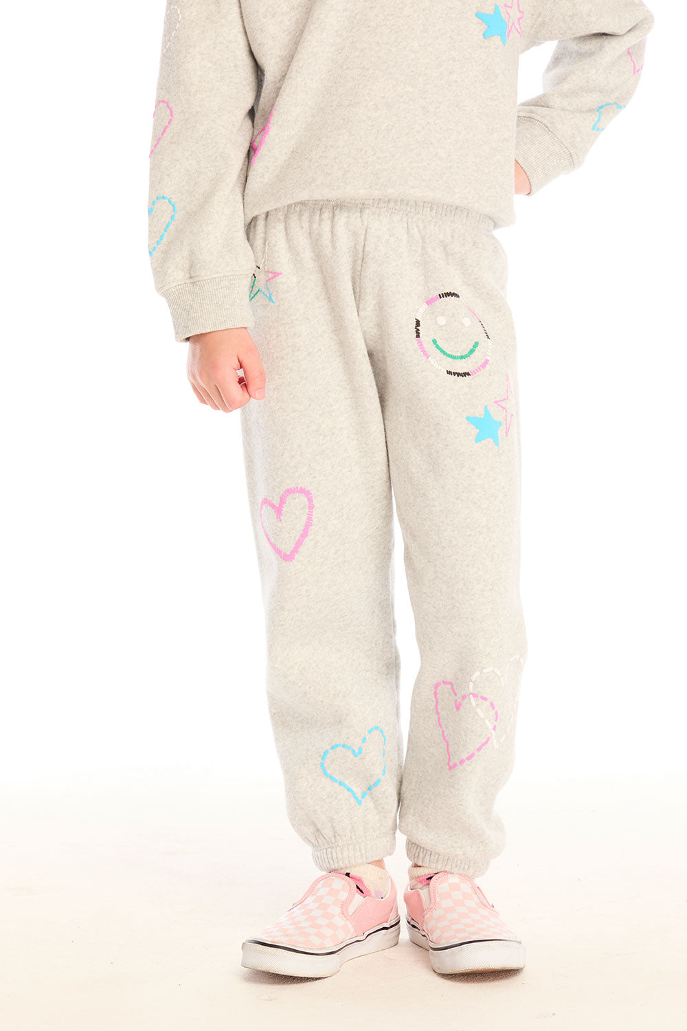Girl wearing Chaser’s light gray Winter Love Pants with colorful designs on a white background
