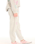 Side view of girl wearing Chaser’s light gray Winter Love Pants with colorful designs on a white background
