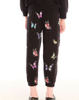 Back view of young girl wearing Chaser’s Butterfly Love pants with colorful butterfly patterns on a white background