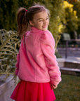 Chaser Kids Camelia Girls Puff-Sleeve Jacket in pink plush fabric, rear three-quarter view outdoors beside a low wall and greenery