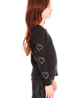 Side view of girl wearing Chaser’s black Love Stitch Hearts Long Sleeve with heart patterns on sleeves on a white background