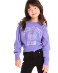 Girl wearing Chaser’s purple Snow Day Athletic Club long sleeve with text and graphics on a white background